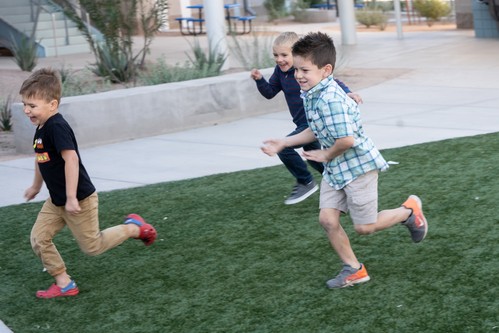 A photo of three boys laughing and running
