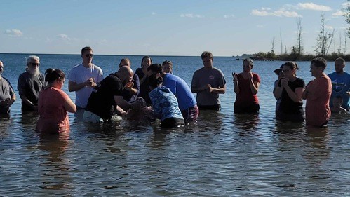 Wellspring community gathers in the lake for a baptism.