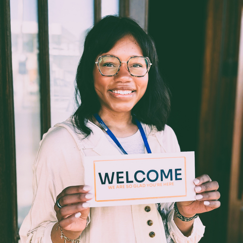 Woman outside of Movement Church greeting guests with a welcome packet.