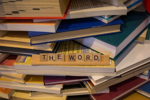 a stack of book with Scrabble letters spelling out 