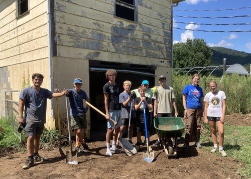 Group of youth with shovels and wheelbarrow working on a mission trip