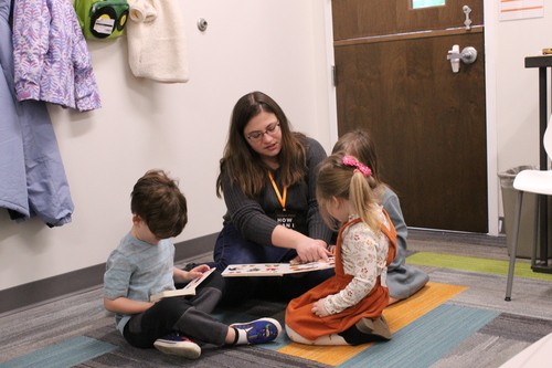 Woman sitting with children to discuss the bible and play during sunday school in Fredericksburg