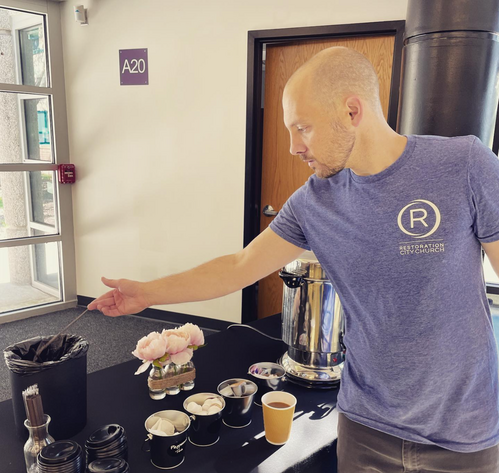 Connect Team volunteer preparing coffee and refreshments in the lobby before Sunday service at Restoration City Church.