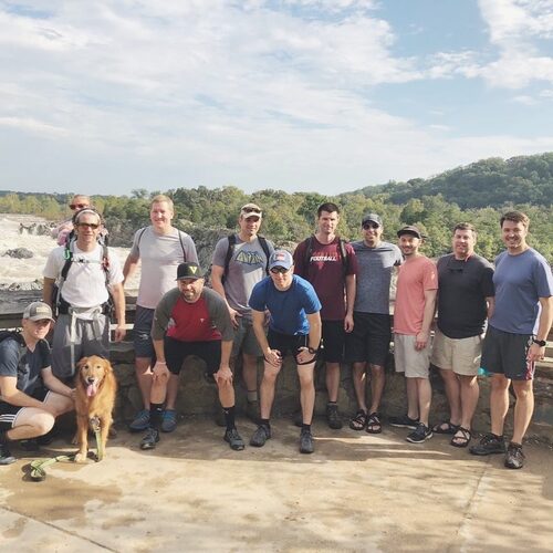 Men&rsquo;s community group from Restoration City Church posing together after a hike near a scenic overlook.