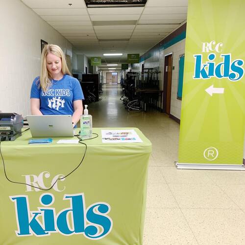 RCC Kids check-in station staffed by a volunteer welcoming families to the children&rsquo;s ministry at Restoration City Church.