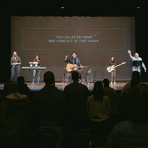 Worship band leading music during a Sunday service at Restoration City Church with lyrics displayed on screen.