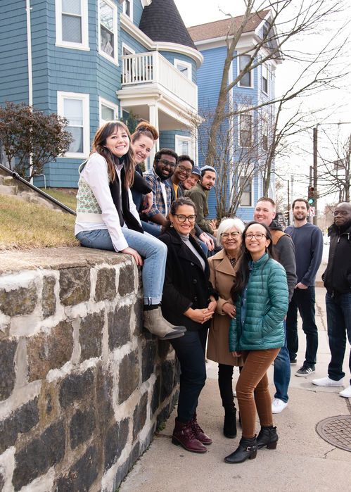 Friends happily hanging out near a wall and taking a picture.