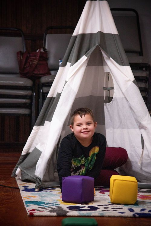 Child with Down syndrome in a tent playing