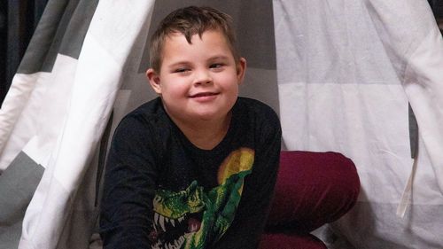Child with Down syndrome playing with blocks in a tent.