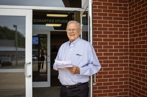 senior adult man smiling with church bulletins in hands