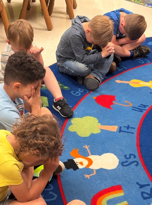little boys bowing their heads to pray