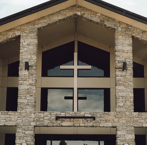 The stone entrance of Southridge Church in Kennewick, with a wooden cross in the windows