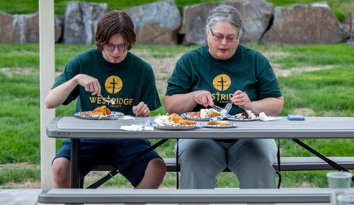 Two volunteers in Westridge Church shirts at a picnic table