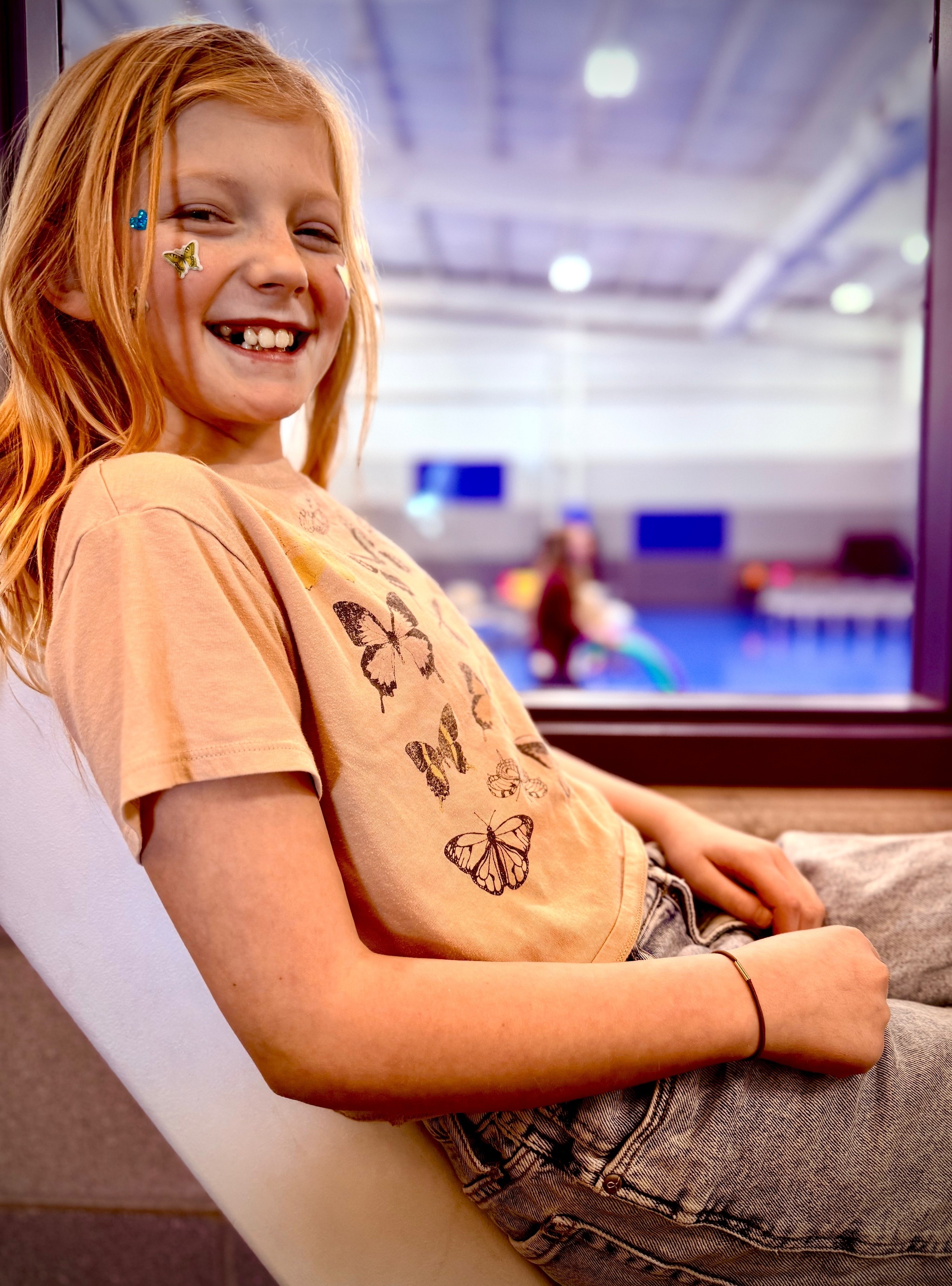 Girl smiling with butterfly stickers at Renewal Kids