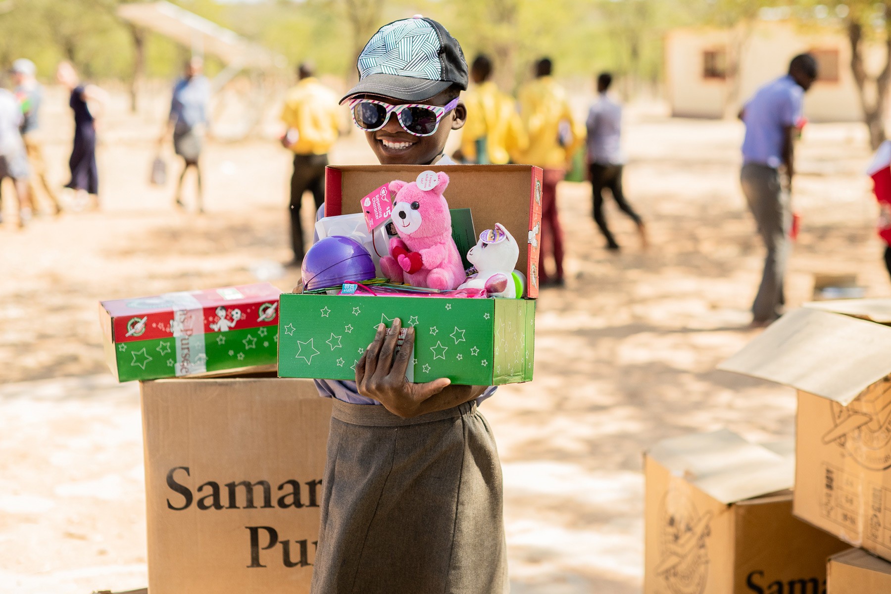 A child smiling while holding a shoebox filled with gifts