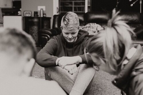 A group of people sitting on the floor, bowing their heads in prayer