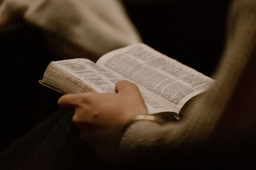 A Bible sitting on someone's lap, open to Ecclesiastes chapter 9