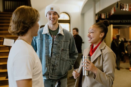 Three people talking in the church lobby and smiling