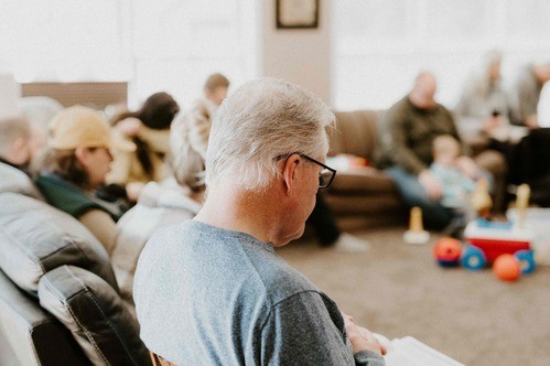 a group of people sitting on couches, focus on elderly man