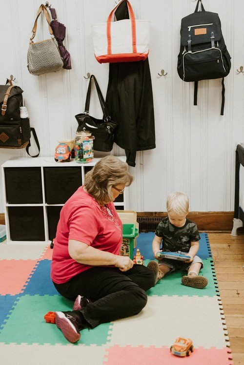 Elderly woman sitting on the ground with child in play