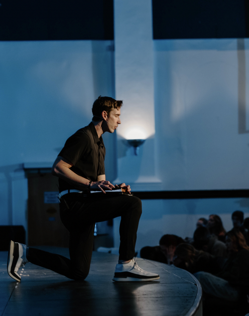 A young blonde woman with eyes closed kneeling down with her hands held out in front of her in worship