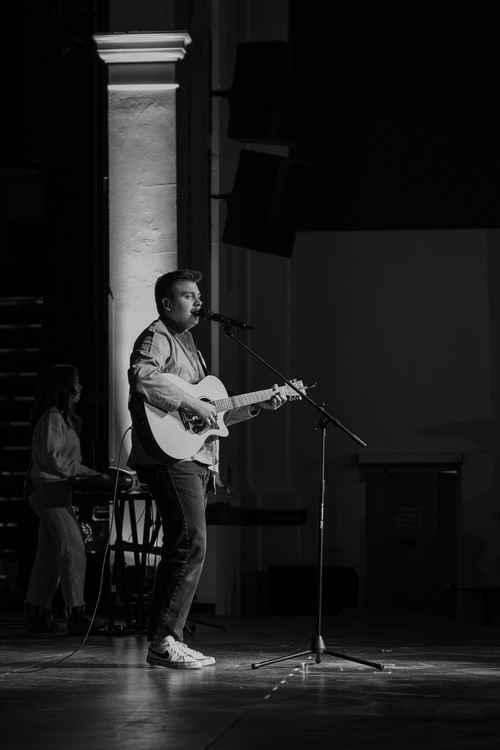 man singing into a microphone and lifting his hand in worship