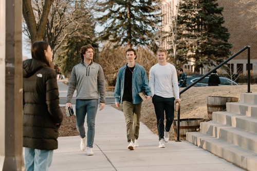 Man with his back turned to camera facing a group of standing people in the background