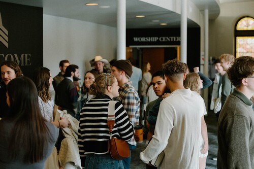 a man baptizing another woman in a tub of water with others in the background cheering