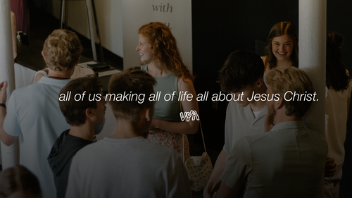 Young man in a congregation with his arms held up in worship, a Bible in his right hand