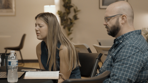 Two people sitting next to each other, hands folded in prayer