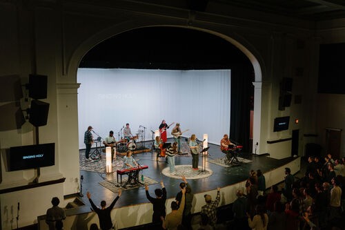 A group of people sitting together and smiling, a young asian woman in the center is laughing