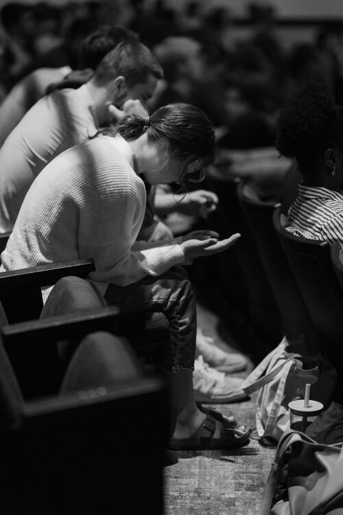 Two people sitting next to each other, hands folded in prayer
