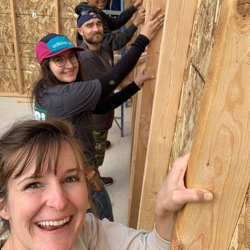3 people holding up newly constructed wall and smiling at camera