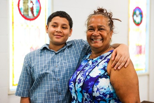 A smiling boy and woman share a hug in front of the stained-glass windows at Pure Hope Church in Mableton, GA