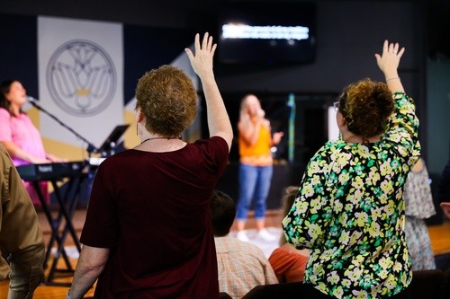 Worshipers lift their hands in praise during Sunday worship at Pure Hope Church