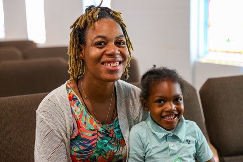A smiling woman and young child sit together in the sanctuary at Pure Hope Church