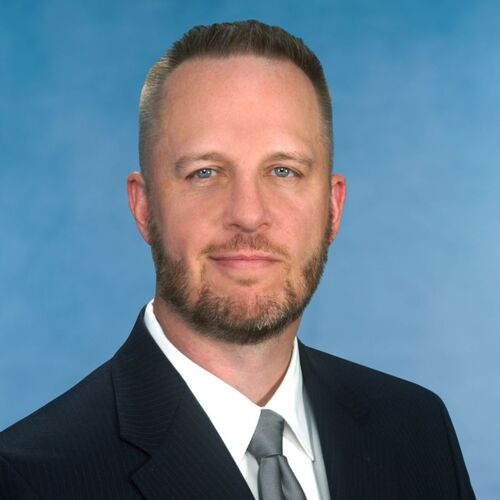 headshot of man with blue background