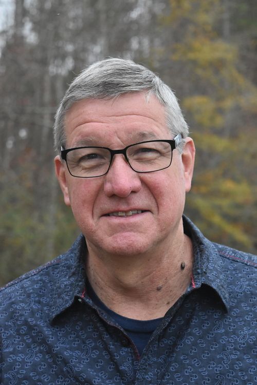 man with glasses with trees in background