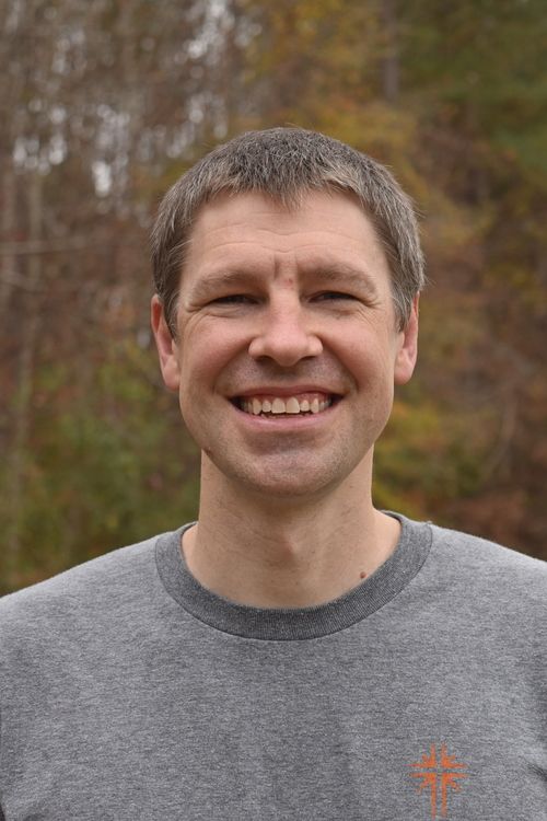 headshot of man with grey shirt