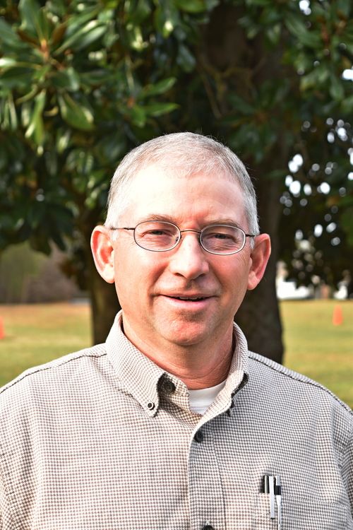 headshot of man with glasses and trees in background