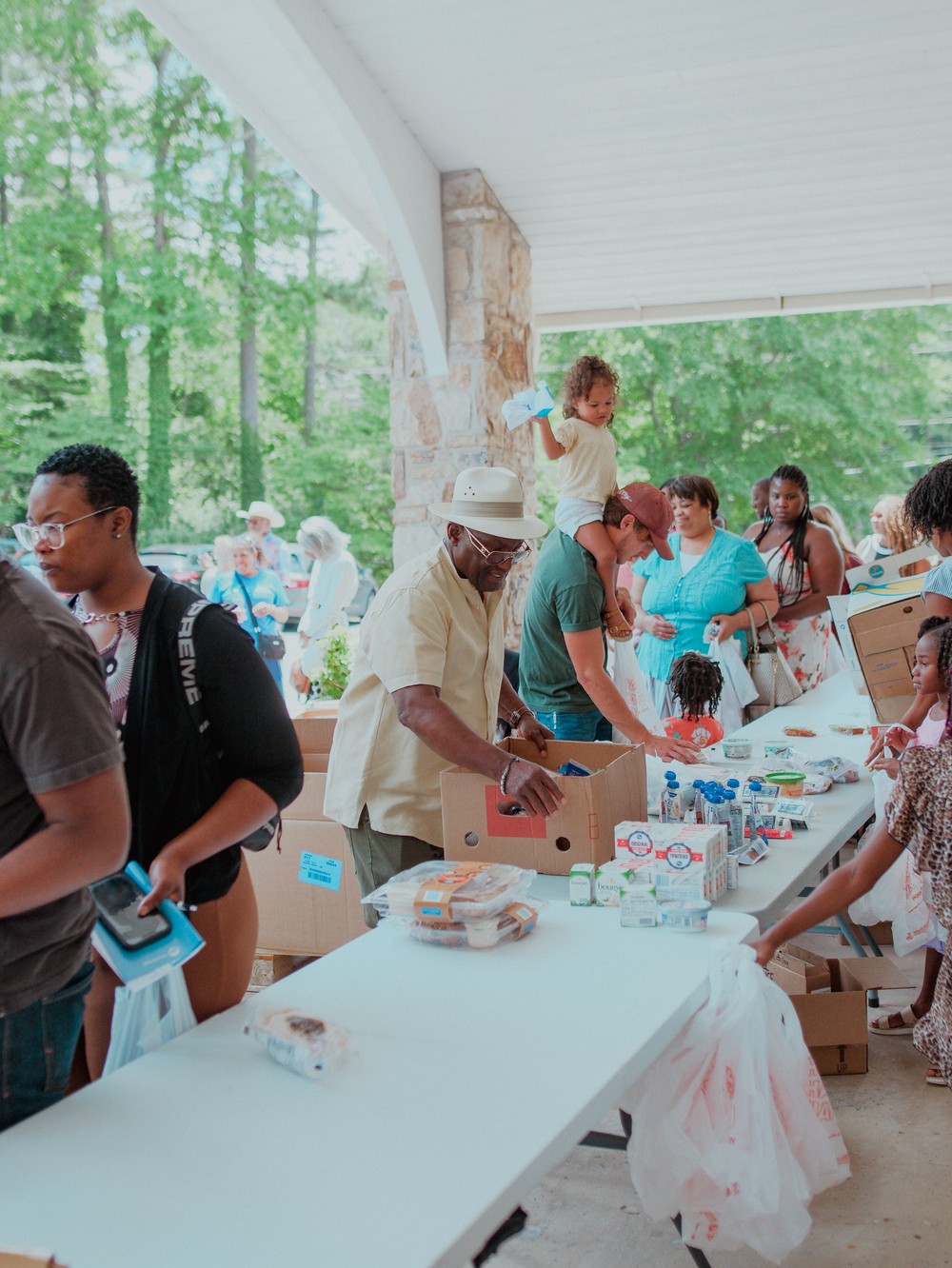 Volunteers handing out food and supplies to neighbors under a covered pavilion