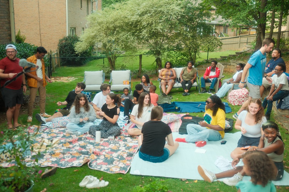 Young adults gathered outside on the grass on a Friday night