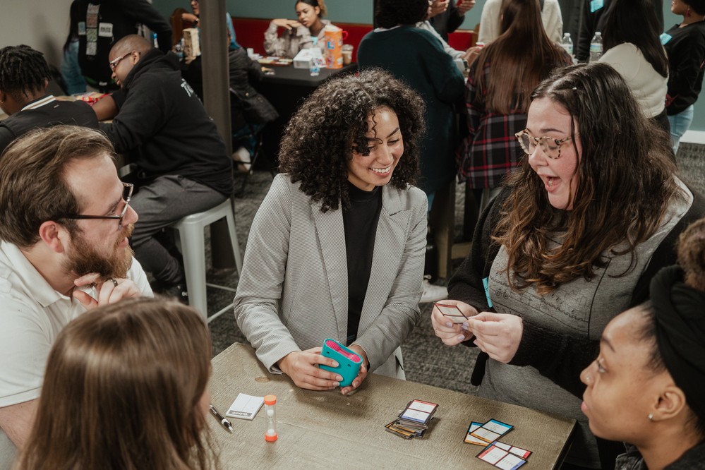 Four young adults around a table, mid conversation