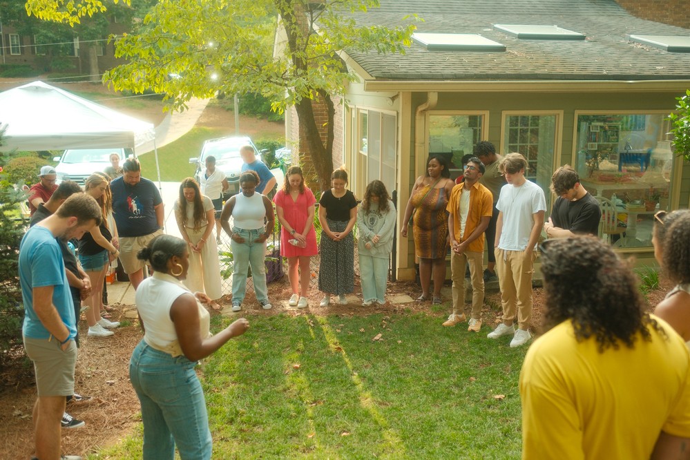 Young adults standing in a circle outside on a Friday night