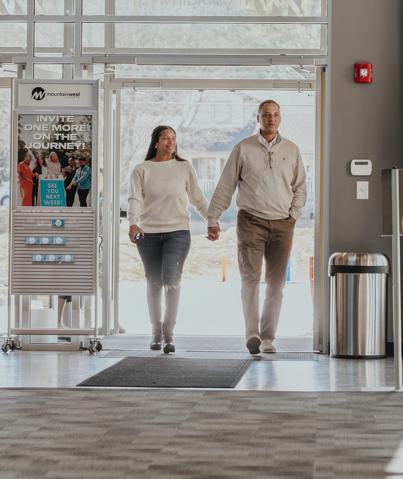 A couple walking hand in hand through the front doors of the Tucker campus
