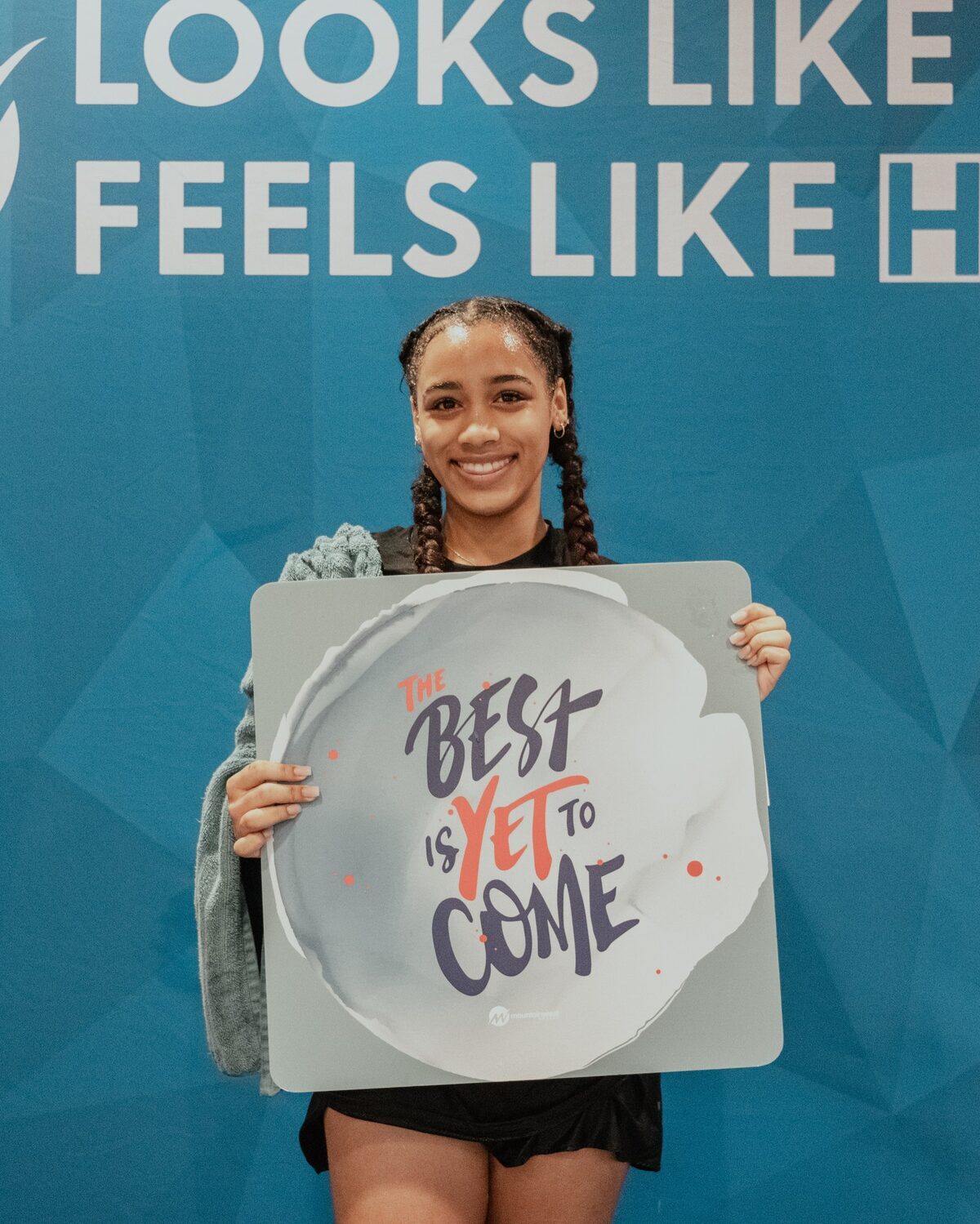 A young woman holding a sign reading The best is yet to come