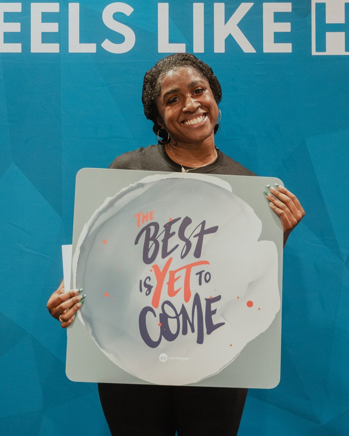 A woman holding a sign reading The best is yet to come