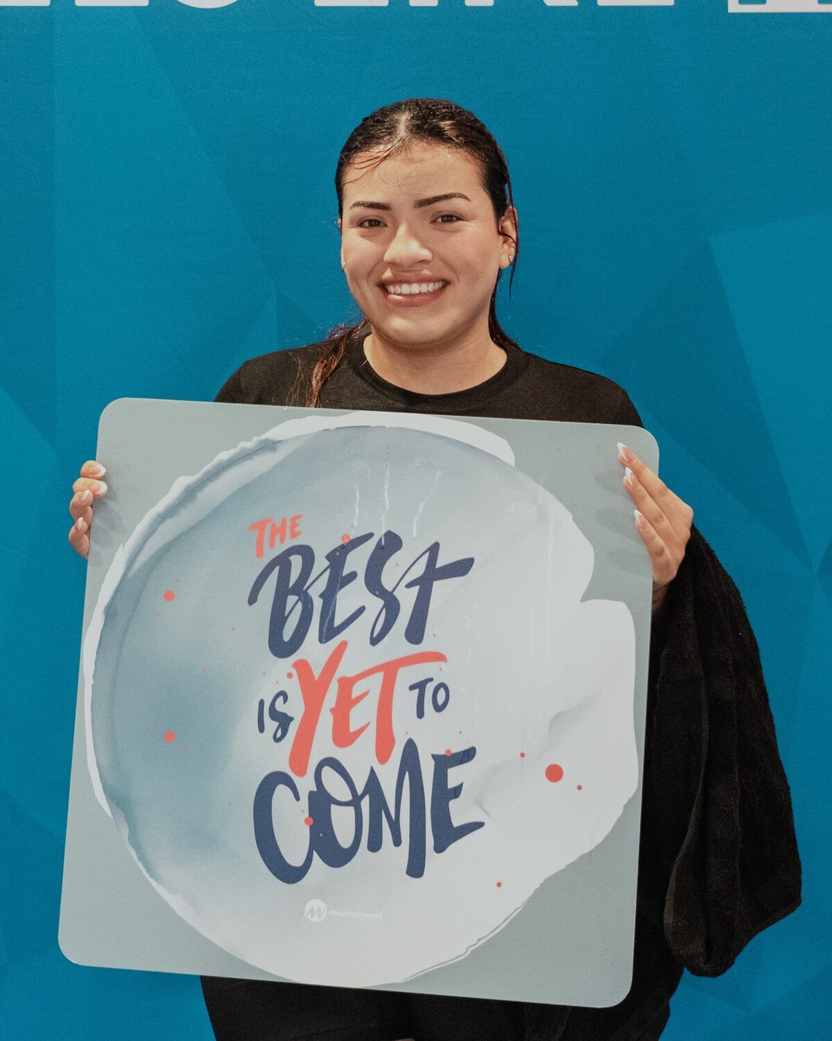 A young woman holding a sign reading The best is yet to come