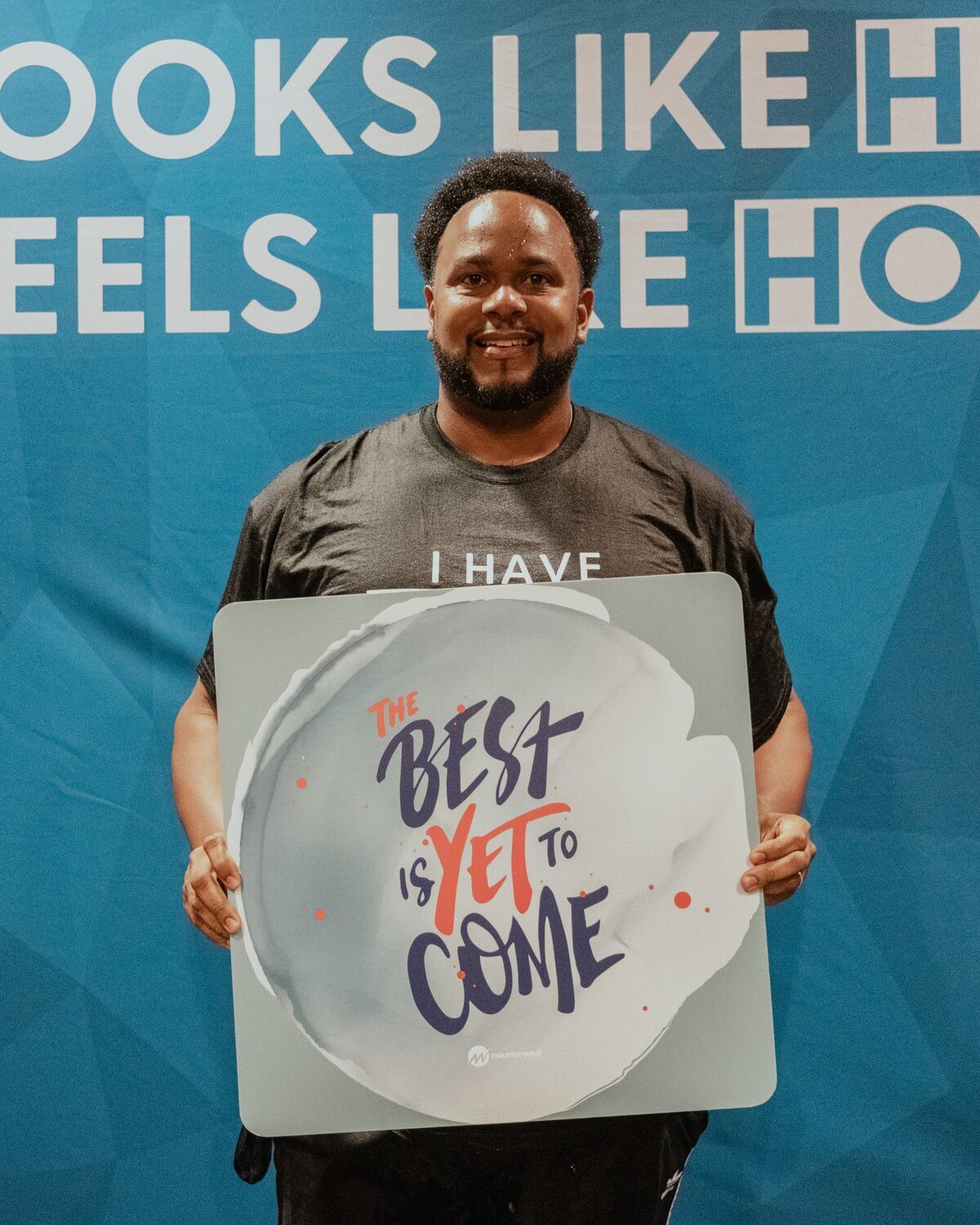 A man holding a sign reading The best is yet to come