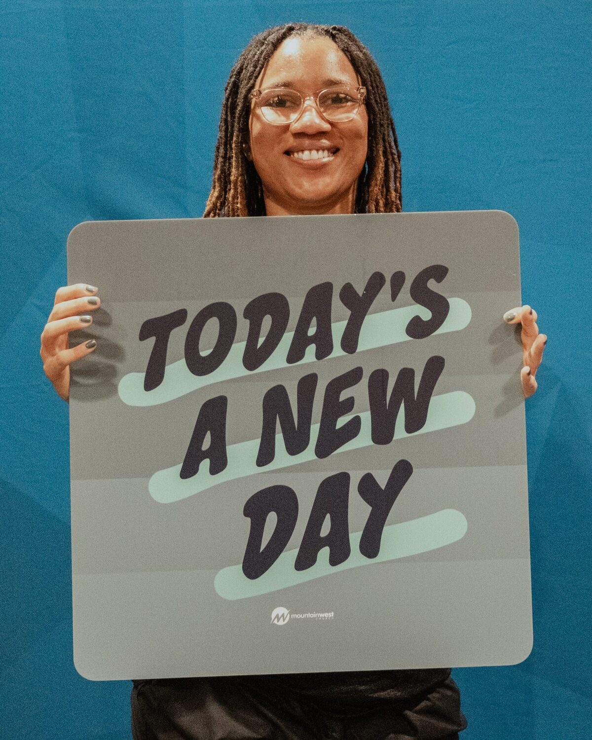 A young woman holding a sign reading Today’s a new day